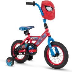 the spiderman bike is red and has blue wheels, with a helmet on it