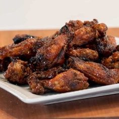 a white plate topped with chicken wings on top of a wooden table