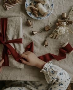 a person holding a red ribbon on top of a piece of cloth next to other items