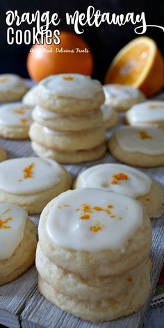 cookies with icing and orange zest are arranged on a cooling rack next to an orange