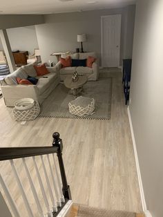 a living room filled with furniture next to a stair case on top of a hard wood floor