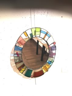 a circular mirror hanging on the side of a wall with multiple colored glass pieces in it