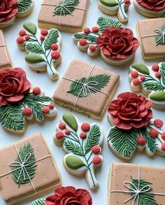 decorated cookies are arranged on a table with red flowers and green leaves in the center