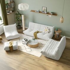 a living room filled with white furniture and decor on top of a hard wood floor