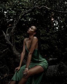 a woman in a green dress sitting on a tree branch