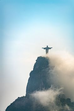 a person standing on top of a mountain with their arms outstretched