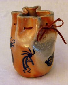 an orange vase with designs on it sitting on a white tableclothed surface,