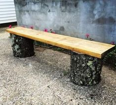 a wooden bench sitting in front of a cement wall with flowers growing on the side