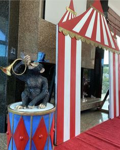 a statue of a monkey on top of a drum in front of a circus tent