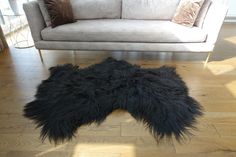 a black sheepskin rug on the floor in front of a couch