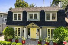 a house with yellow doors and windows in front of some bushes on the side of it