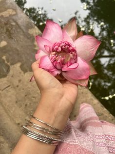 a woman holding a pink flower in her hand