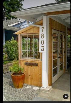 a small wooden building sitting next to a potted plant