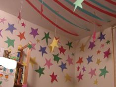 colorful stars are hanging from the ceiling in this child's room with bookshelves