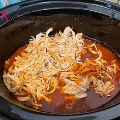 the food is being cooked in the crock pot with sauce and shredded cheese on top