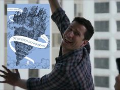 a man holding up a book with an image of a city on it and the words o nomos do avereno