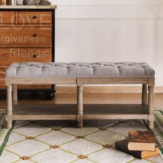 a bench sitting on top of a rug in front of a dresser and chest of drawers