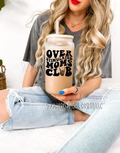 a woman sitting on a bed holding a drink in her hand with the words over my mops club printed on it