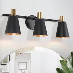 three light bathroom fixture with black shades and gold accents in a modern style home setting