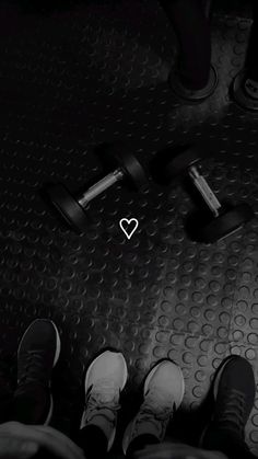 two people standing on top of a metal floor with dumbbells in front of them