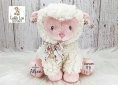 a pink and white stuffed sheep sitting on top of a white fur covered floor next to a wooden wall