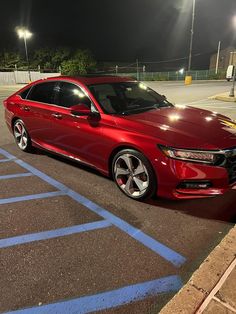 a red honda accord parked in a parking lot at night with its lights turned on