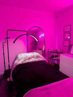 a bedroom with pink lighting and black bedding