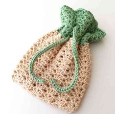 a crocheted bag with a green bow on the front and bottom, sitting on a white surface