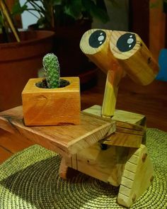 a wooden toy sitting on top of a table next to a potted green plant