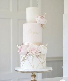 a three tiered white cake with pink flowers on top