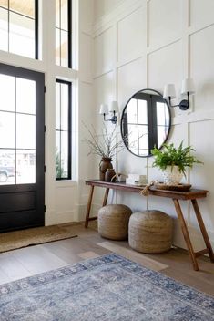 a living room with a rug, mirror and two stools