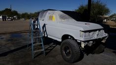 a white truck parked on top of a parking lot next to a blue scaffold