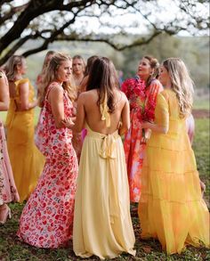 a group of women standing next to each other wearing dresses and holding bouquets in their hands