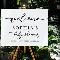 a welcome sign for a baby shower is displayed in front of some potted plants