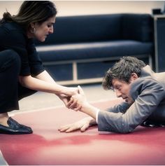 a woman kneeling down next to a man on the ground