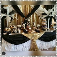 a table topped with lots of cakes and desserts covered in black and gold decorations