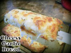 a cheesy garlic bread is being cut into pieces