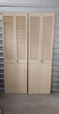 two white closet doors with shutters in front of a storage room door that is closed