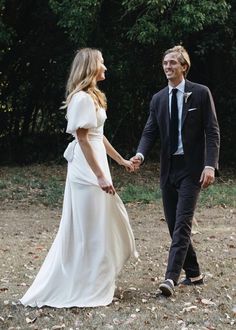 a man and woman holding hands while walking