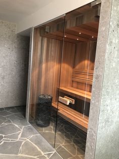 an empty sauna in the corner of a room with glass walls and stone flooring