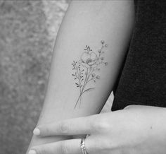 a black and white photo of a woman's arm with a flower tattoo on it