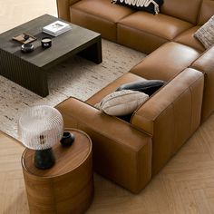 a brown leather couch sitting on top of a wooden floor next to a coffee table