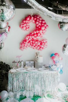 a table with balloons and streamers on the wall in front of it that says 2