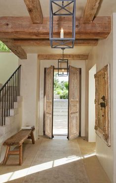 an open door leading into a hallway next to a wooden bench and stairs in a home