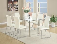 a glass dining table with white chairs and flowers in the vase on the rug next to it