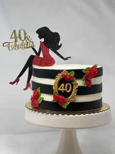 a black and white striped cake with red roses on the top, decorated with a silhouette of a woman