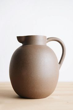 a brown vase sitting on top of a wooden table