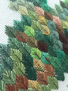 a close up view of some green and brown knitted fabric with leaves on it