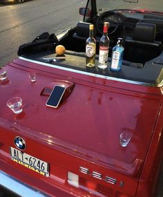 an old red car with bottles and glasses in the back