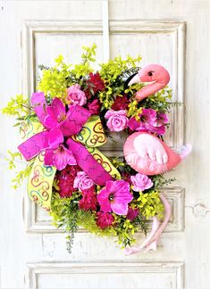 a flamingo wreath on a door with pink flowers and green foliages in front of it